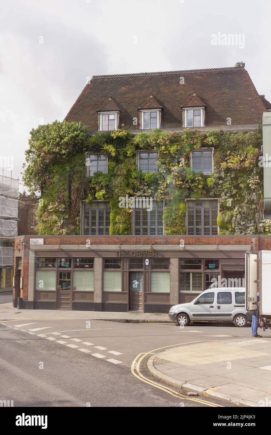 A vertical shot of a car parked next to a beautiful traditional house decorated with plants in London Stock Photo