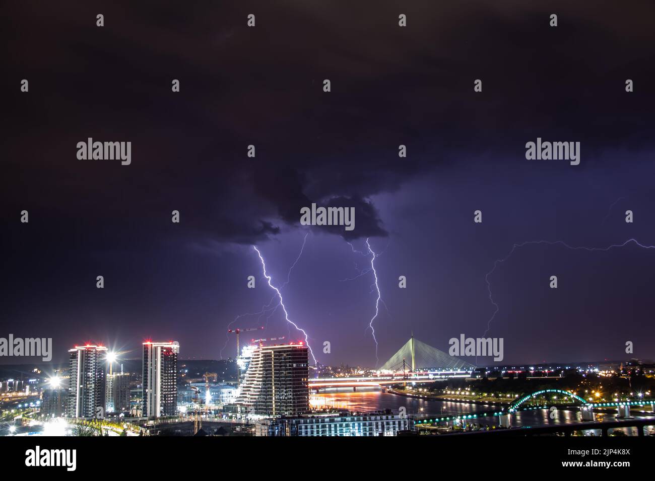 Very cloudy sky, lightning and thunder above the Belgrade (capital of Serbia) sky, panoramic view of the city and the river with bridges. Stock Photo