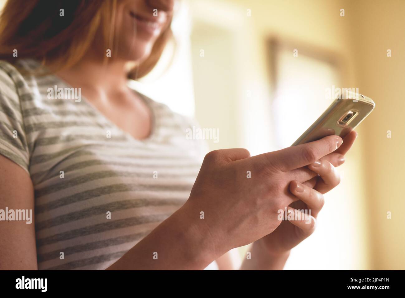 Catching up on some early morning texts. an unrecognizable woman using a cellphone in the morning at home. Stock Photo