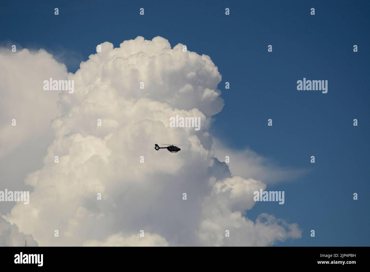 An Airbus Deutschland MBB-BK helicopter flies in front of towering cumulus clouds over Santa Fe, New Mexico. Stock Photo
