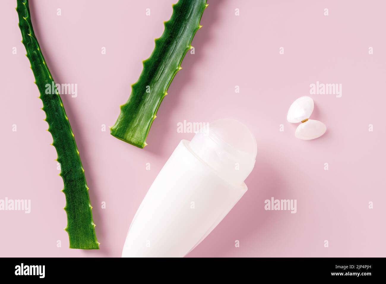 Roll on antiperspirant deodorant and fresh aloe leaves over pastel pink background. Concept of  organic cosmetics, natural toiletries, body care. Stock Photo