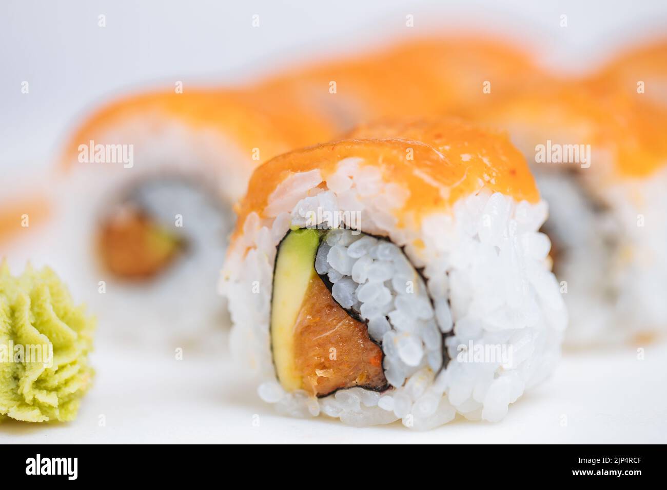 Sushi rolls on platter, bright background. Served with wasabi and
