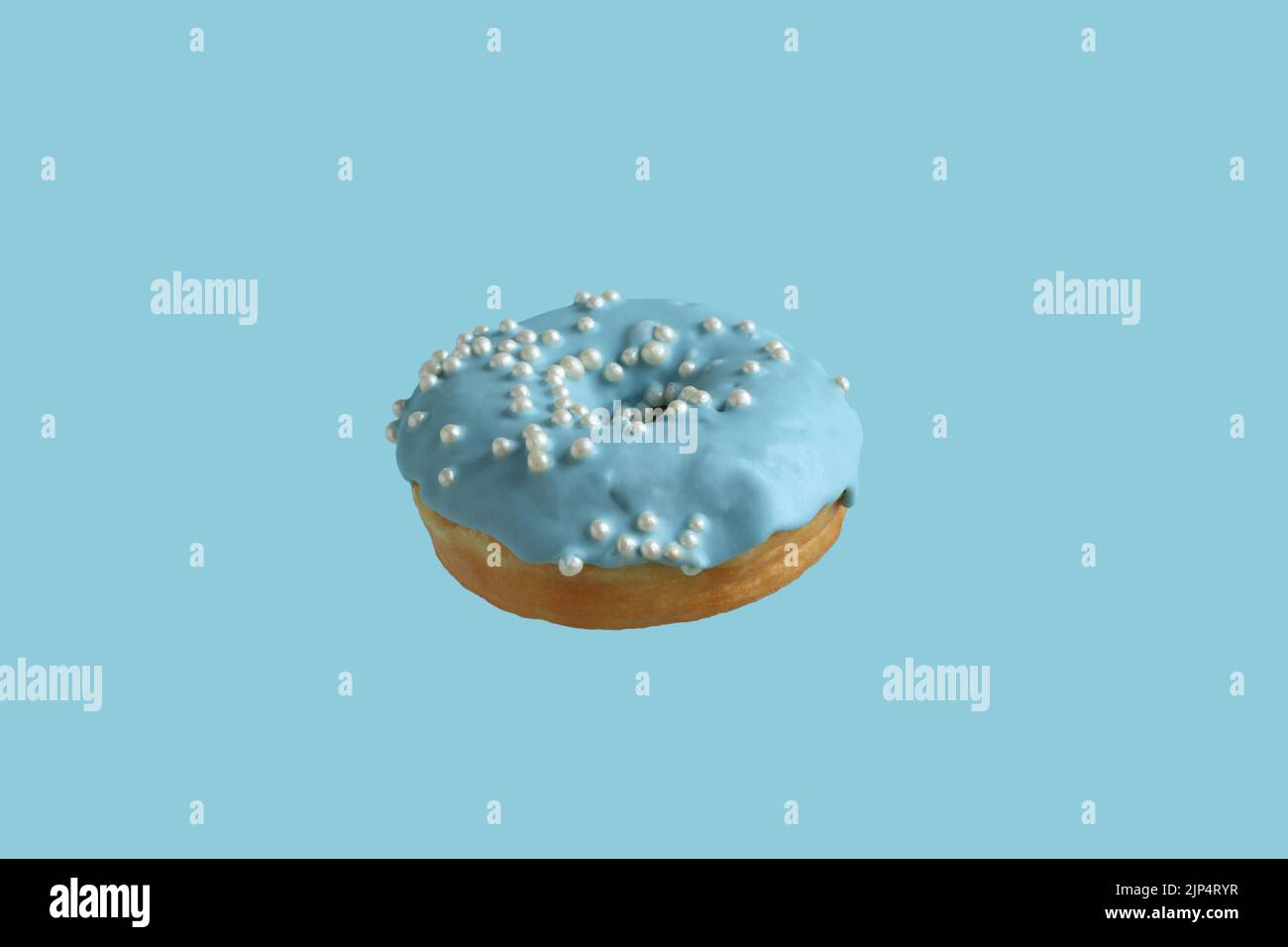 Donuts covered with pale blue icing and sprinkled with pearl sugar beads on a light blue background. Closeup. Stock Photo
