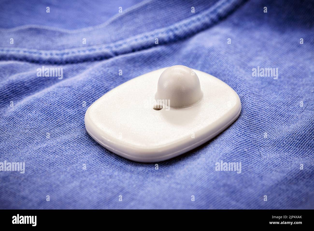 anti-theft device used in commerce, tag or anti-theft tag on blue shirt, electronic alarm Stock Photo