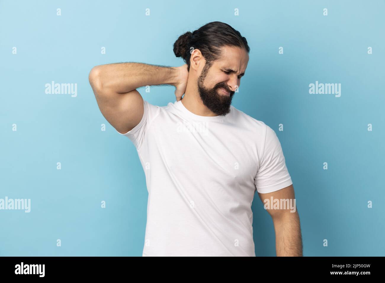 Portrait of man with beard wearing white Tshirt touching neck, feeling
