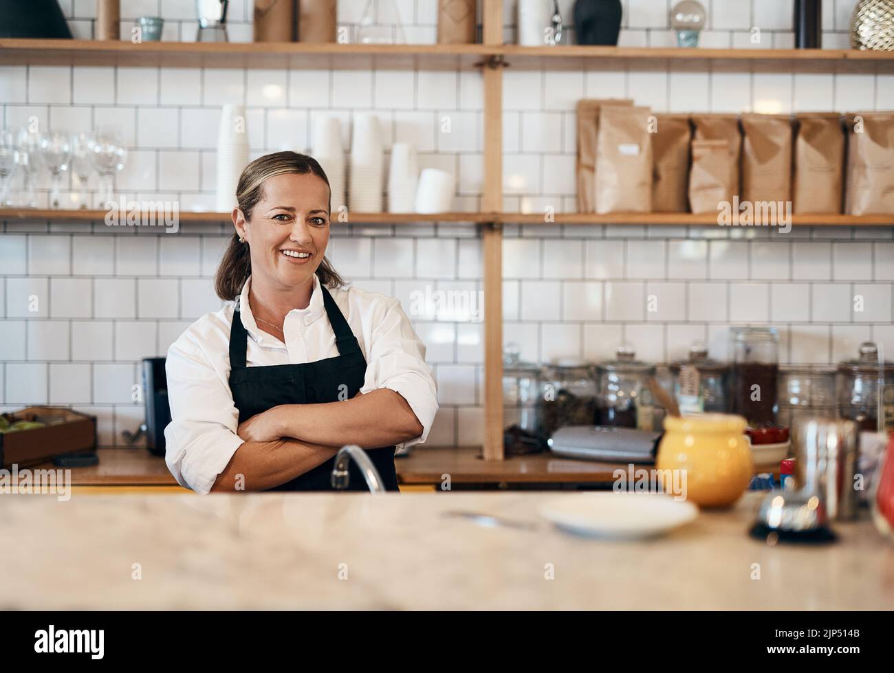 Business owner, barista standing with arms crossed, looking confident and proud while working at a restaurant. Cafe worker, employee and entrepreneur Stock Photo