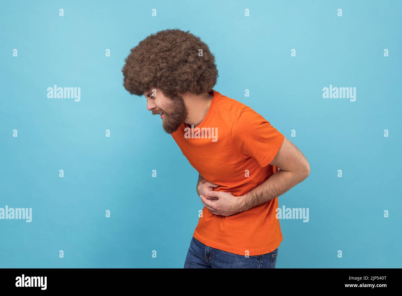 Stomach pain. Side view of sick sad unhealthy man with Afro hairstyle