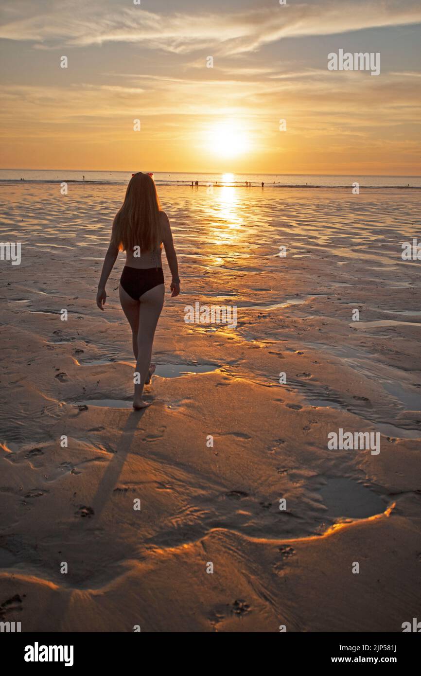 Young girl walking towards sunset at Polzeath beach. Cornwall England Stock Photo