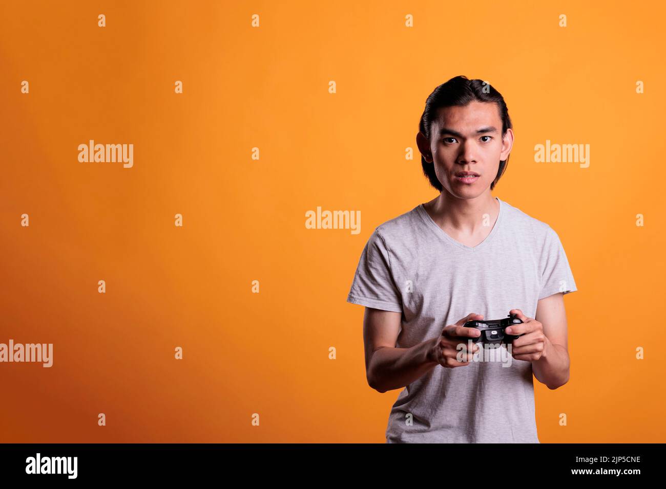 Foto de man with a controller standing in front of a PC console TV screen  with a steam controller playing popular free to play game Roblox do Stock