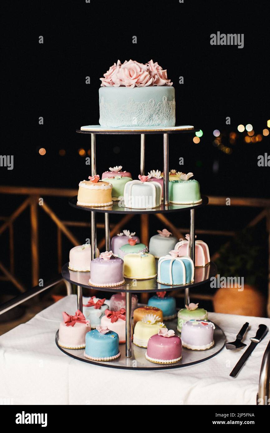 Multilevel wedding cake with flowers and bows. Lots of little cakes. Stock Photo