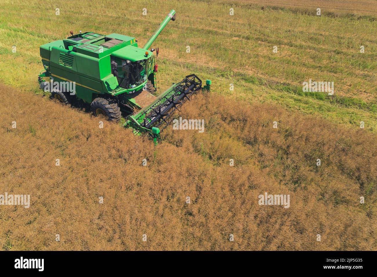 Crop season. Aerial side view of a green combine harvester with a ...