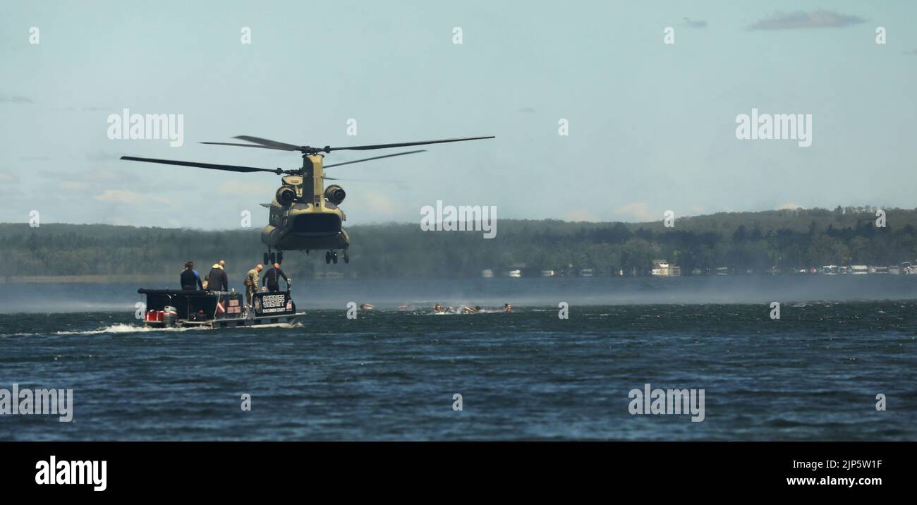 A Roscommon County Sheriff’s boat transports Soldiers assigned to the U.S. Army 20th Special Forces Group (Airborne) (SFG), Alabama National Guard, during helocast operations from a CH-47 Chinook operated by 1st General Support Aviation Battalion, 111th Aviation Regiment, Florida Army National Guard, at Lake Margrethe in Grayling, Mich., Aug. 11, 2022. This year’s exercise brings over 7,400 people from 19 states and 4 coalition countries to northern Michigan. (U.S. Army National Guard photo by Staff Sgt. Tegan Kucera) Stock Photo