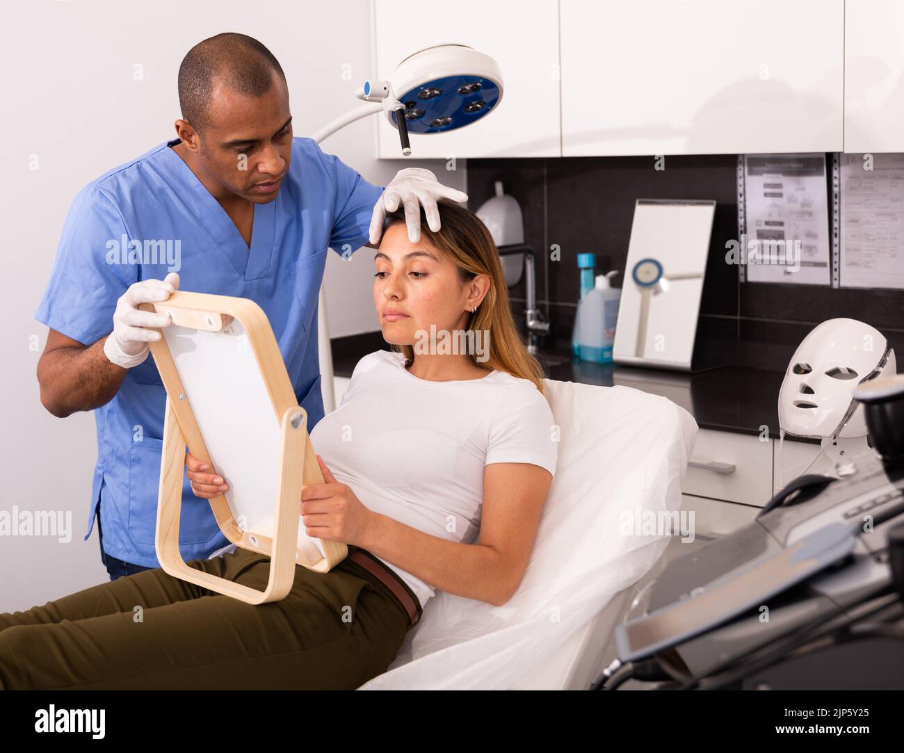 Beautician explaining woman hardware facial procedure Stock Photo - Alamy