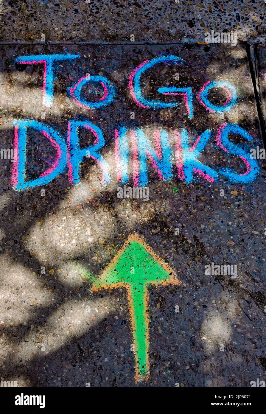 A chalk sign on the sidewalk advertises drinks to-go at The Blind Tiger, Aug. 13, 2022, in Bay Saint Louis, Mississippi. Stock Photo