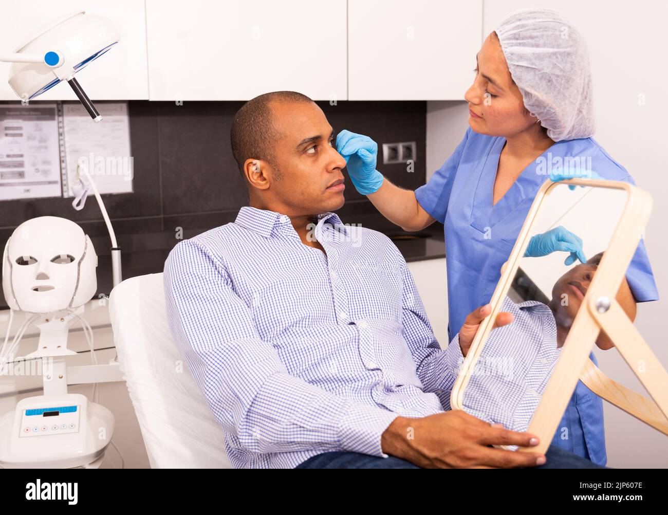 Female cosmetician explaining man upcoming hardware facial procedure ...