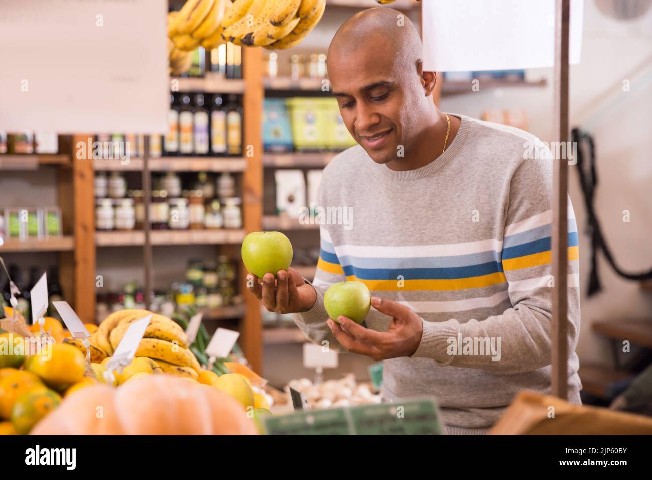 Latin American shopper choosing fresh apples in grocery store Stock