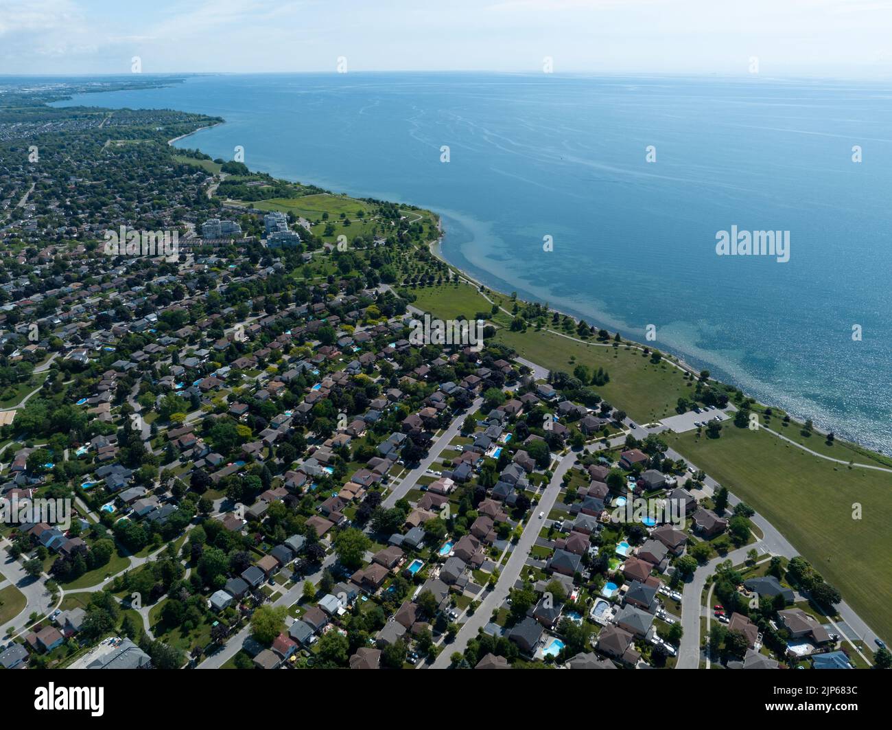 A high, aerial view above a large residential neighbourhood next to a lake. Stock Photo