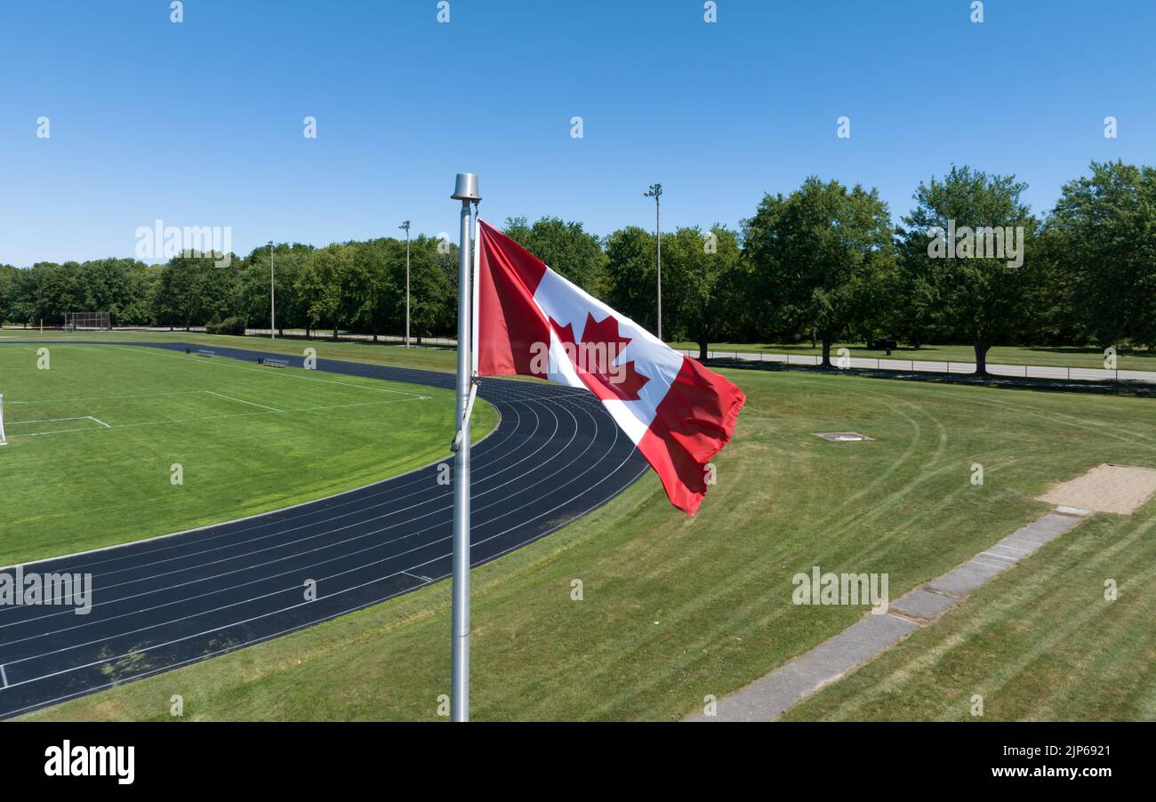 A waving Canadian flag is seen closeup at a residential track and field centre, seen on a sunny summers day. Stock Photo