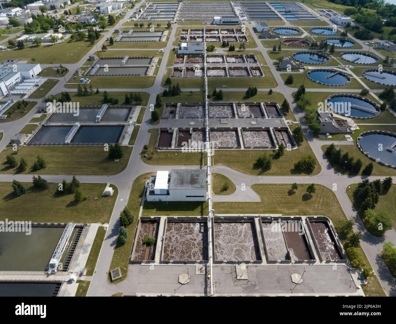 A high-angle aerial view above a large, vast water treatment plant on a sunny day. Stock Photo