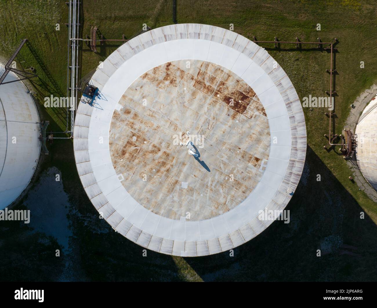 A direct overhead aerial view above a white crude oil storage tank on a sunny day. Stock Photo