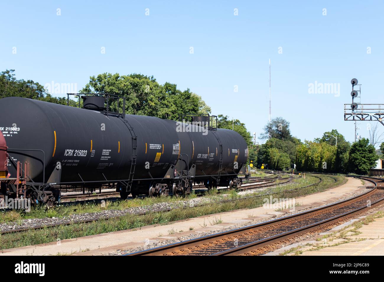 Three oil tanker freight train cars are seen together, stationary in a rail yard during the day. Stock Photo