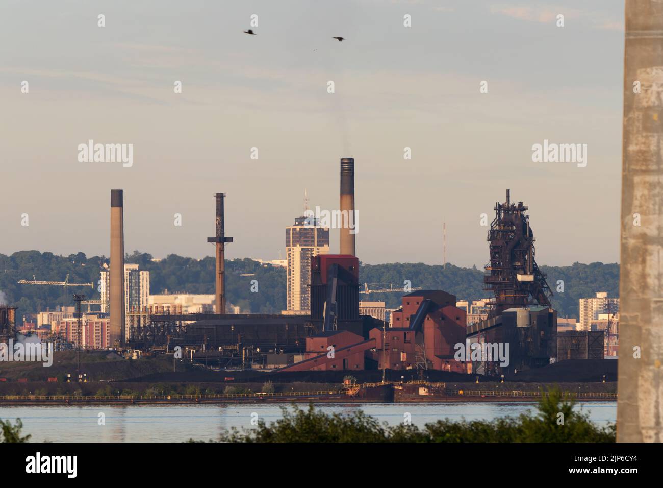 A landscape view at dawn of a manufacturing sector, large factories and refineries with tall smokestacks in the Port of Hamilton. Stock Photo
