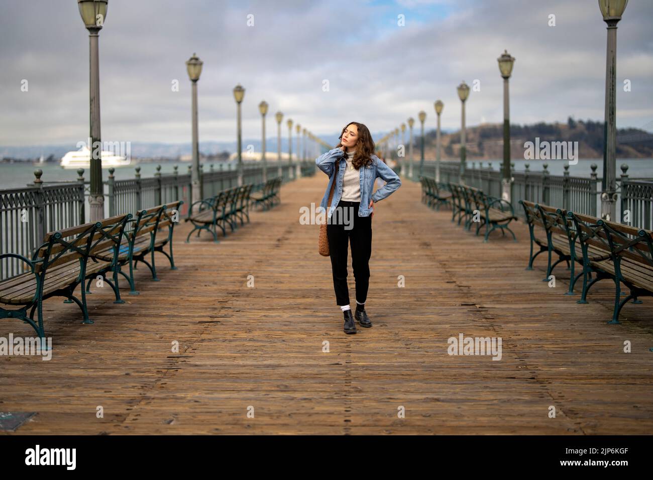 Unposed Portrait of Young Woman on Pier 7 Walking Towards Camera with San Francisco Bay in the Background Stock Photo