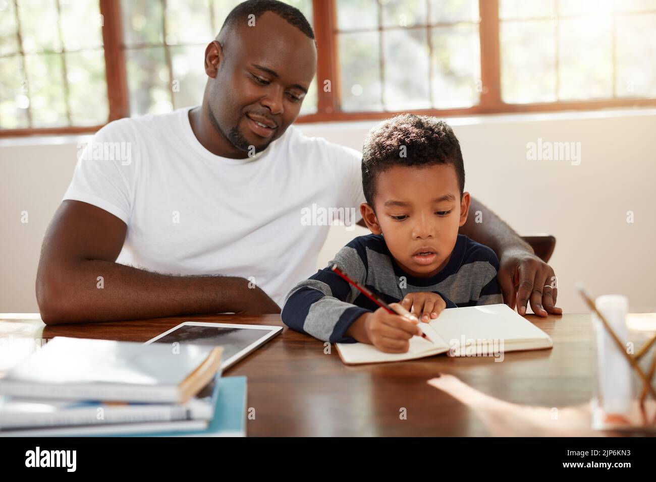 Making sure he works hard. a handsome young father helping his son with ...