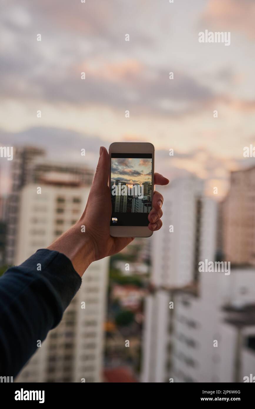 The perfect spot to take some shots. an unrecognizable man taking a photo of the city with his cellphone outside. Stock Photo