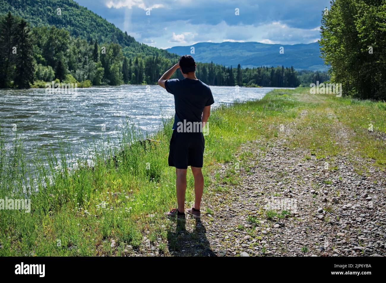 Rear view of the mature man standing on the bank of the river Stock Photo