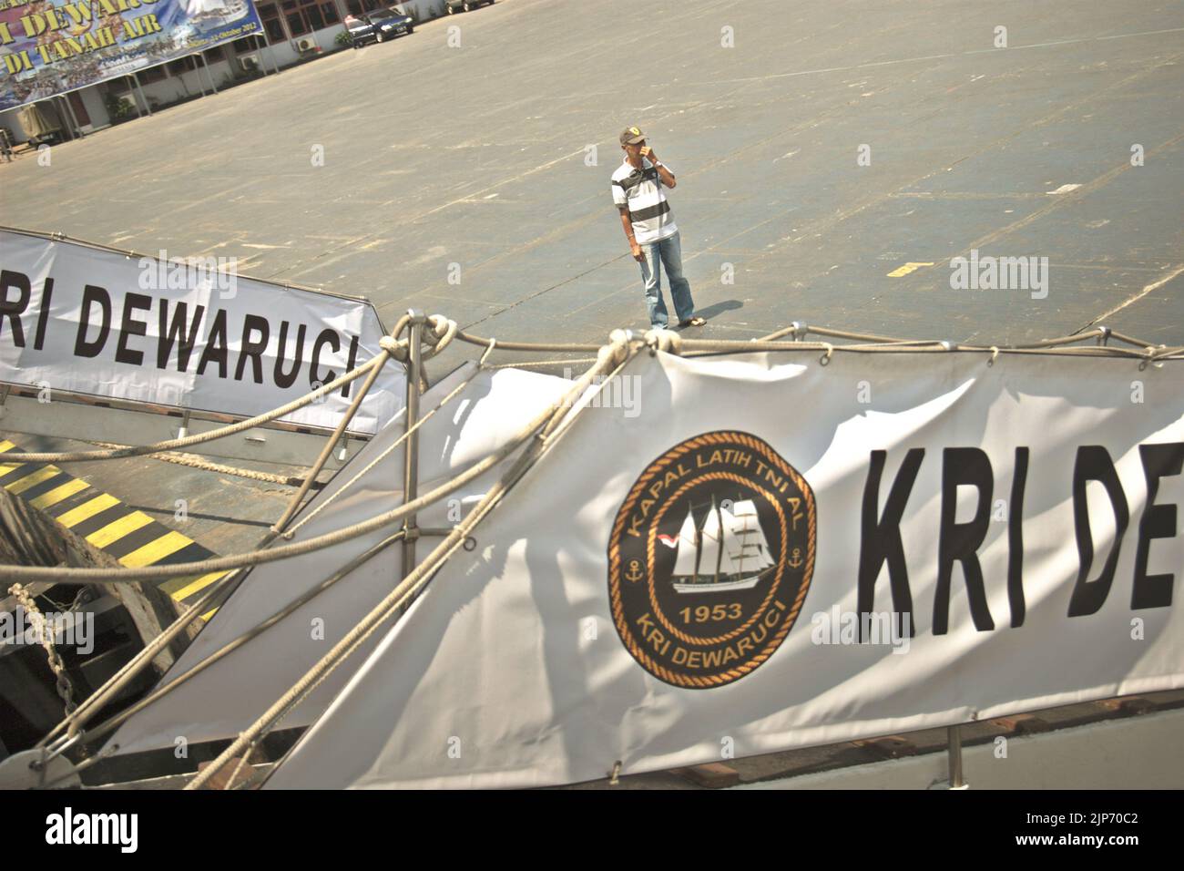 A visitor standing on harbour platform, in a foreground of the ladders of KRI Dewaruci (Dewa Ruci), an Indonesian tall ship, as the barquentine type schooner is opened for public visitors at Kolinlamil harbour (Navy harbour) in Tanjung Priok, North Jakarta, Jakarta, Indonesia. Stock Photo