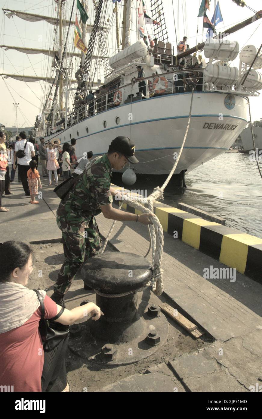 A military officer untying a rope of KRI Dewaruci (Dewa Ruci), an Indonesian tall ship, as it is setting up a sail after the barquentine type schooner being opened for public visitors at Kolinlamil harbour (Navy harbour) in Tanjung Priok, North Jakarta, Jakarta, Indonesia. Stock Photo