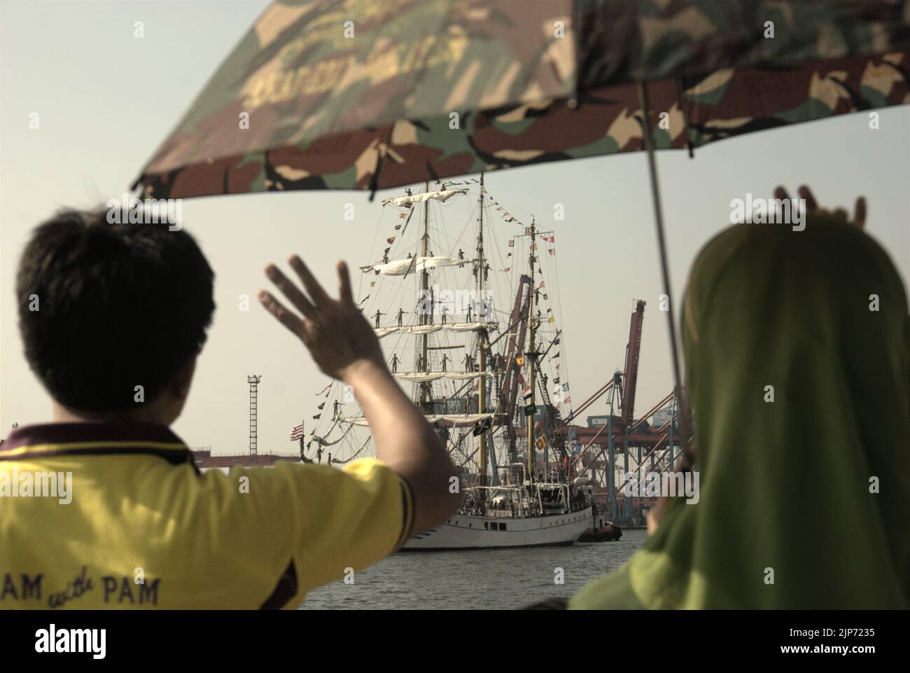 Families and visitors waving goodbye to KRI Dewaruci (Dewa Ruci), an Indonesian tall ship, as the barquentine type schooner starting to sail after being opened for public at Kolinlamil harbour (Navy harbour) in Tanjung Priok, North Jakarta, Jakarta, Indonesia. Stock Photo