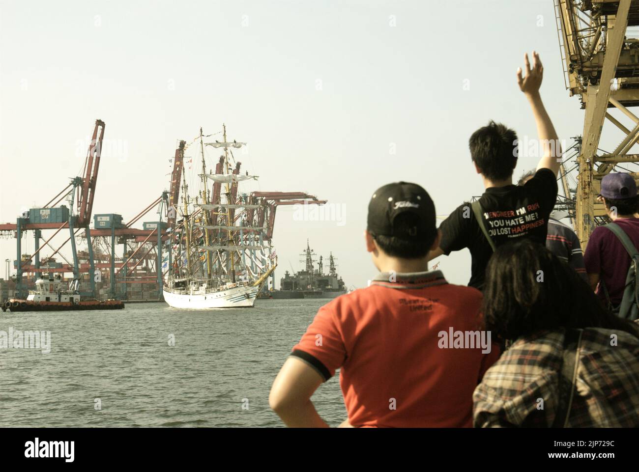 Families and visitors waving goodbye to KRI Dewaruci (Dewa Ruci), an Indonesian tall ship, as the barquentine type schooner starting to sail after being opened for public at Kolinlamil harbour (Navy harbour) in Tanjung Priok, North Jakarta, Jakarta, Indonesia. Stock Photo
