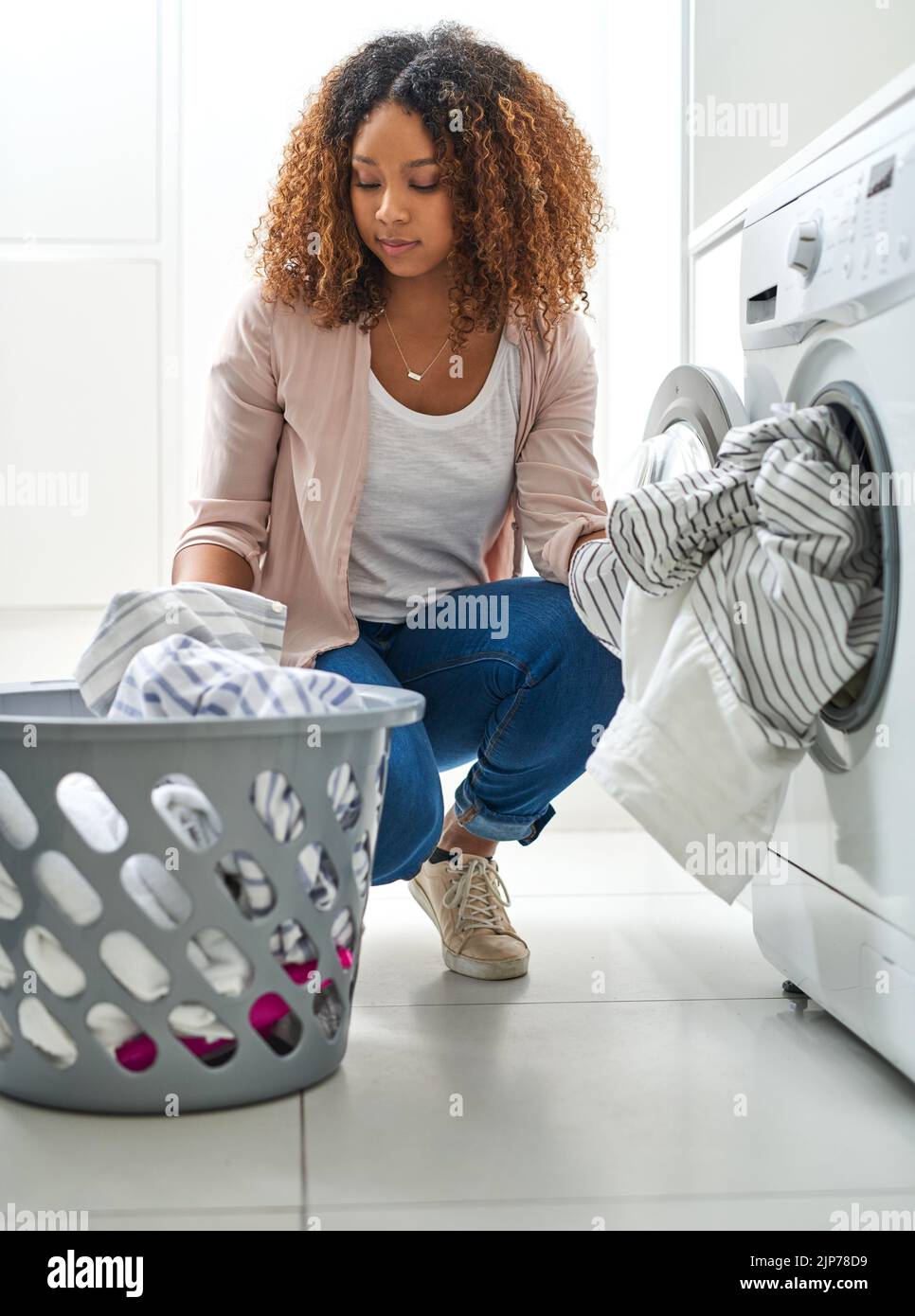 Its a chores type of day. a young attractive woman doing laundry at ...