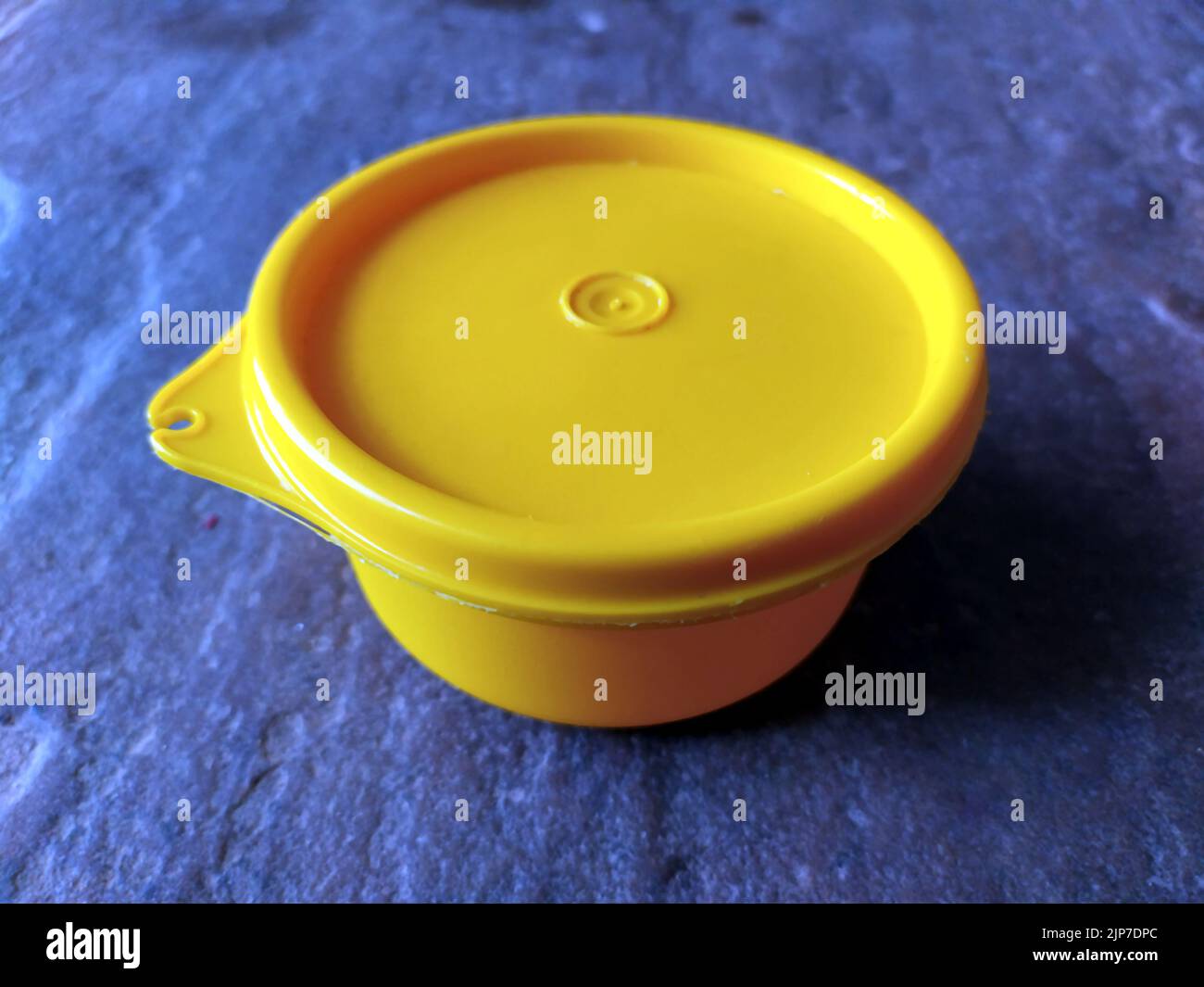 yellow plastic container box on stone background Stock Photo