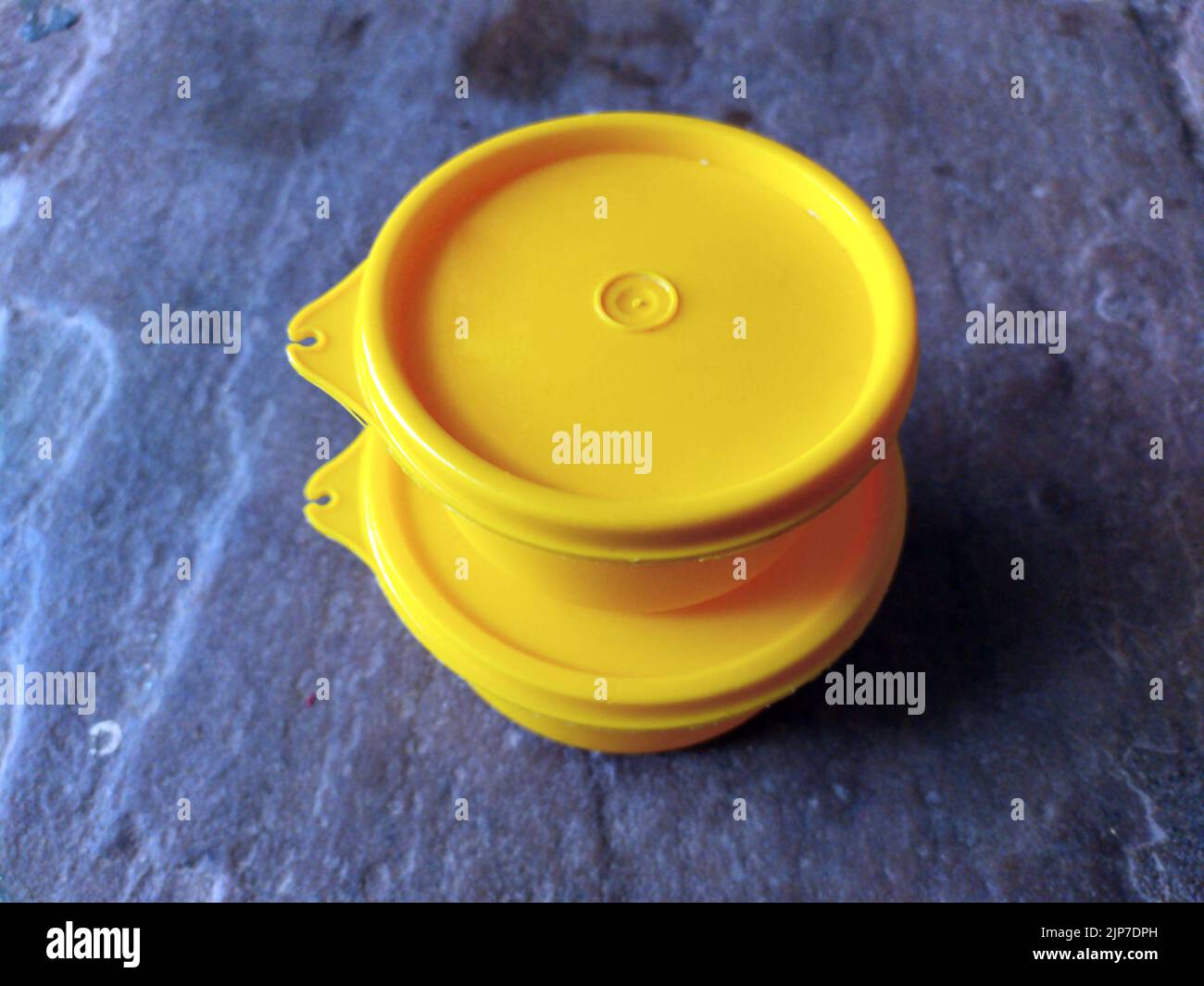 yellow plastic container box on stone background Stock Photo