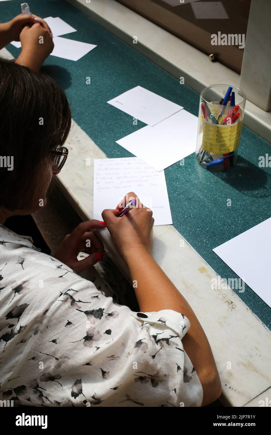 Odessa, Ukraine. 12th Aug, 2022. A woman seen writing a letter to the front. Letter to the front. Project from Ukrpochta (Ukrainian Post).Every large and small Ukrainian can express his gratitude to the modern heroes by sending a picture or a postcard to any branch of Ukrposhta. All children's drawings and postcards with words of support and hope for a peaceful life from adults and children will be given to military personnel in hot spots, as well as to medics and rescuers, representatives of ground defense, and communal services throughout the country. (Credit Image: © Viacheslav Onyshchenko Stock Photo