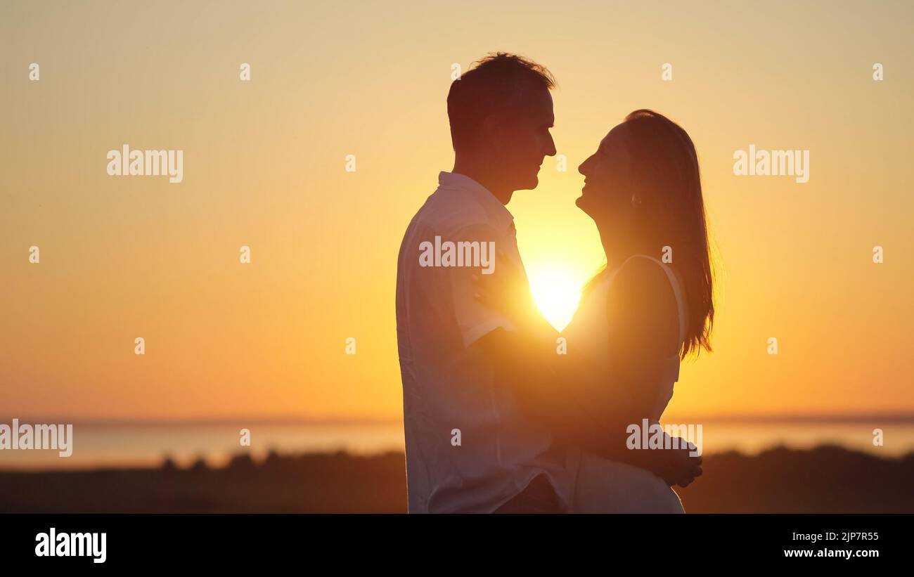 Couple stands showing pure love to each other at back sunset Stock Photo