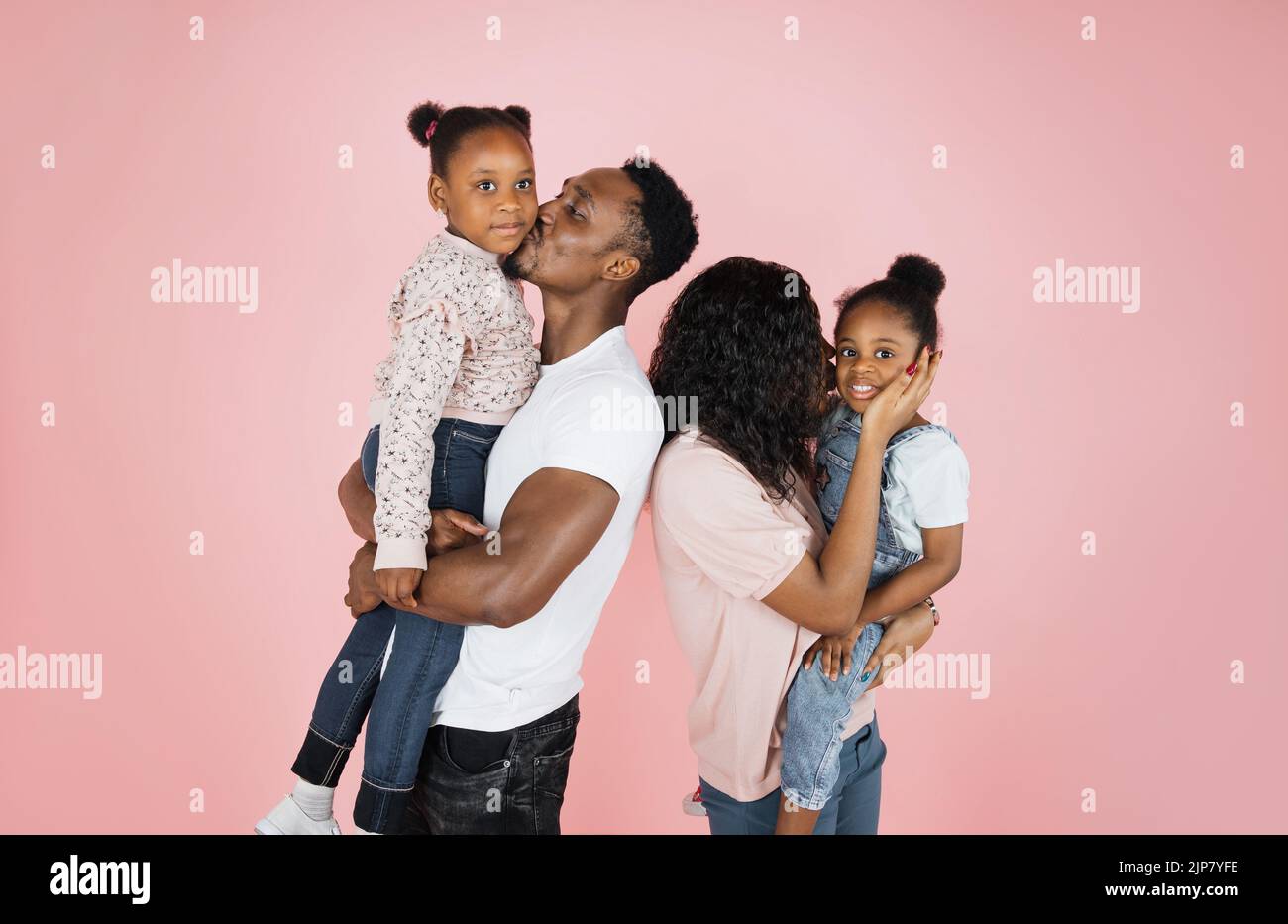 Happy african american woman holding and kissing one daughter, and ...