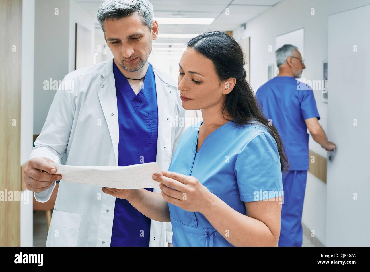 Experienced cardiologist with female nurse analyzing patient cardiogram. Department of cardiology at hospital Stock Photo