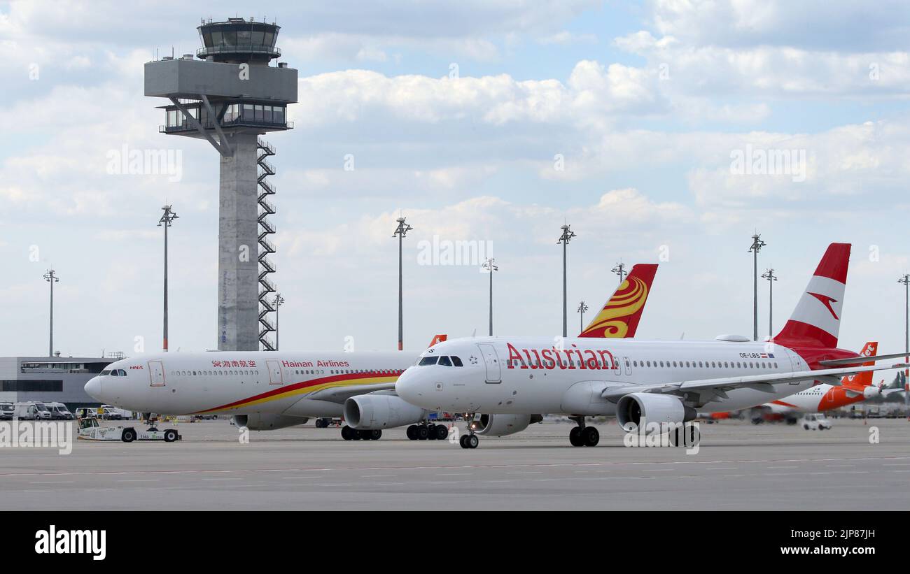 12 August 2022, Brandenburg, Schönefeld: An Airbus A330-300 aircraft of Hainan Airline stands in front of the tower of Berlin Brandenburg Airport before the Chinese airline's maiden flight from BER. On the right, an Airbus A320 of Austrian Airline. Photo: Wolfgang Kumm/dpa Stock Photo