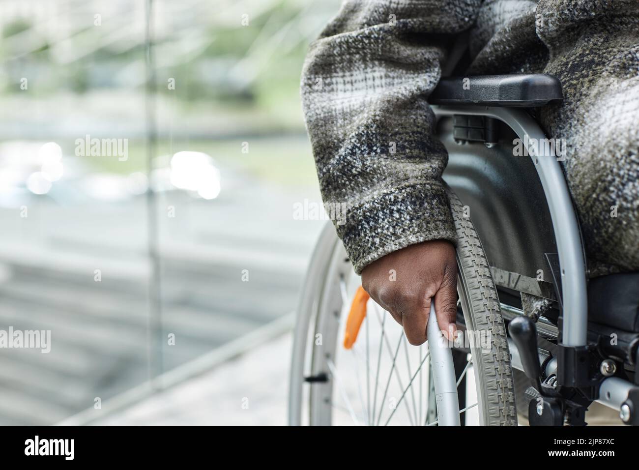 Closeup of unrecognizable black woman in wheelchair pushing wheel, copy space Stock Photo