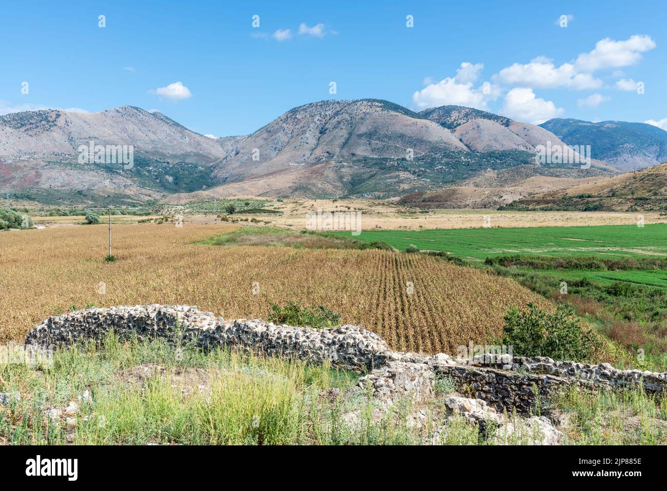 Idyllic landscape with agricultural fields surrounded by mountains in southern Albania near the abandoned Orthodox monastery Stock Photo