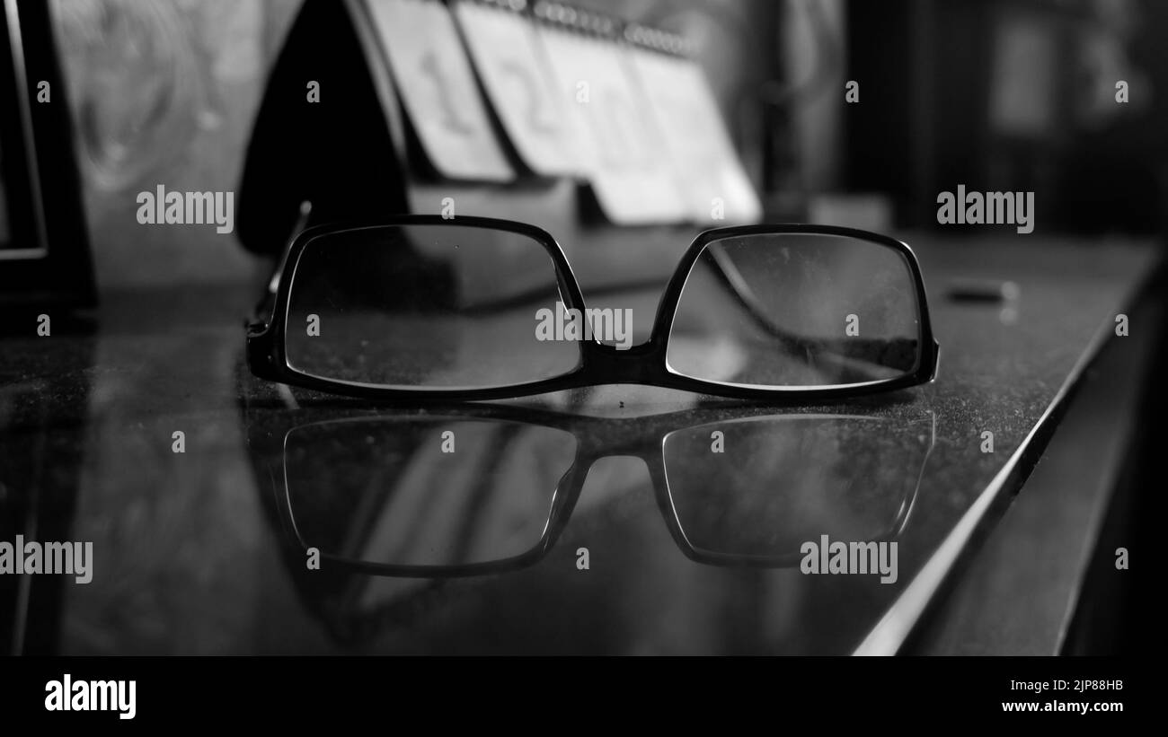 A closeup grayscale shot of glasses on the table full of dust Stock Photo
