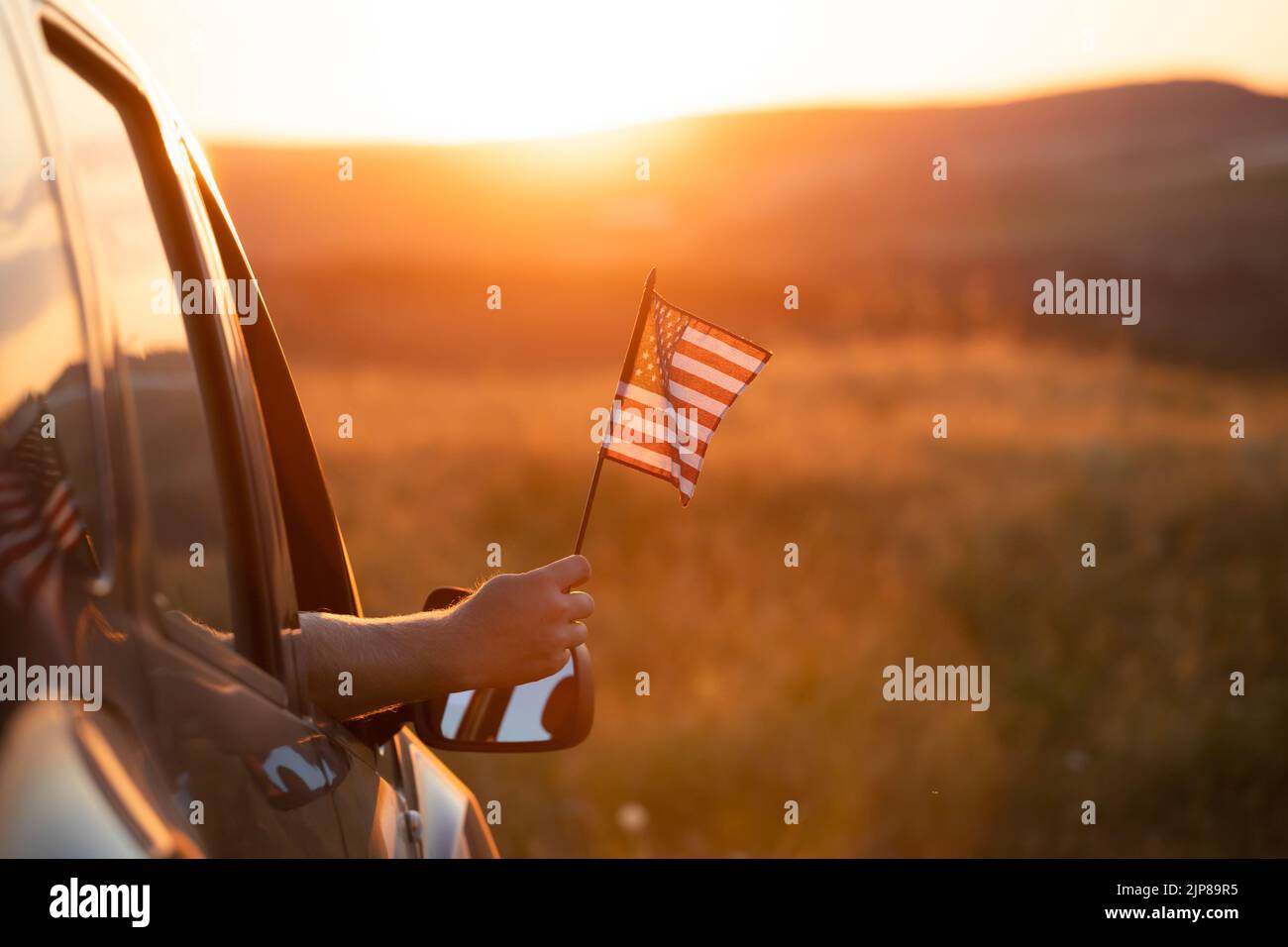 Man holding an American flag on a road trip. Independence Day or traveling in America concept. Stock Photo