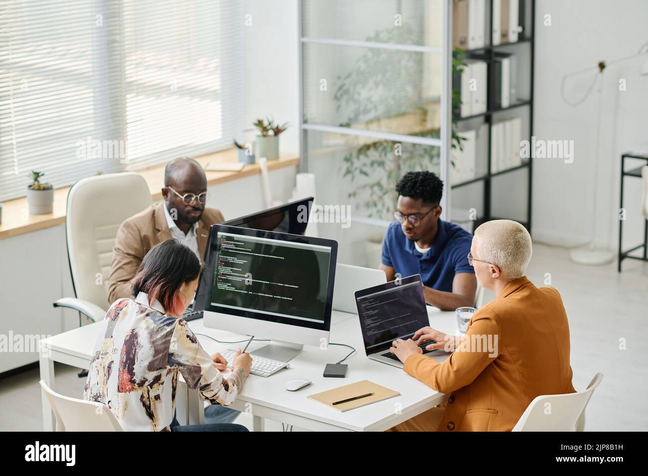 High angle view of Group of programmers working on computer and laptop with codes during teamwork at office Stock Photo