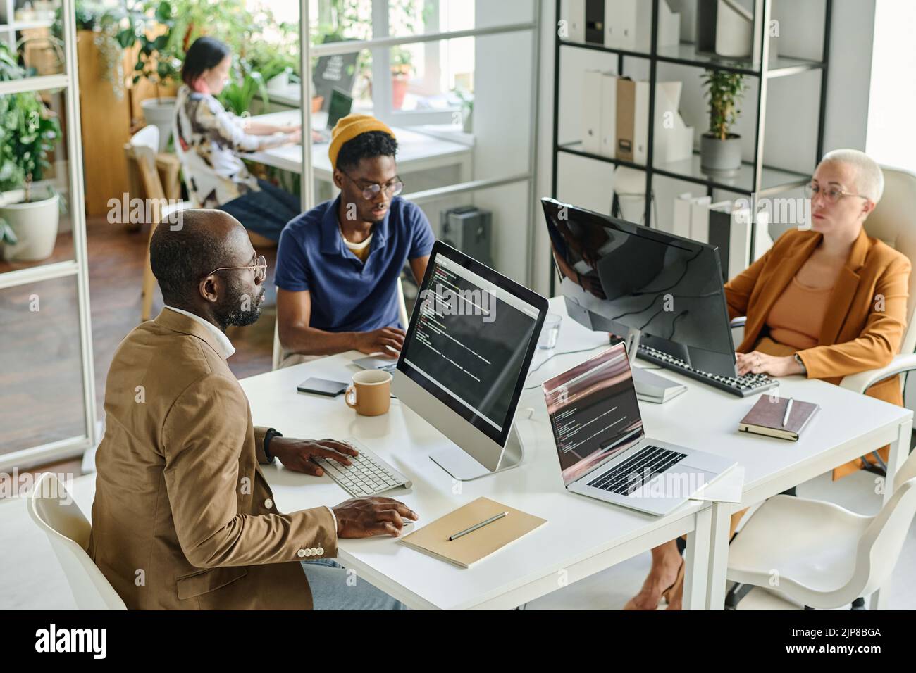 High angle view of programmers developing new software on computers together at table at meeting Stock Photo