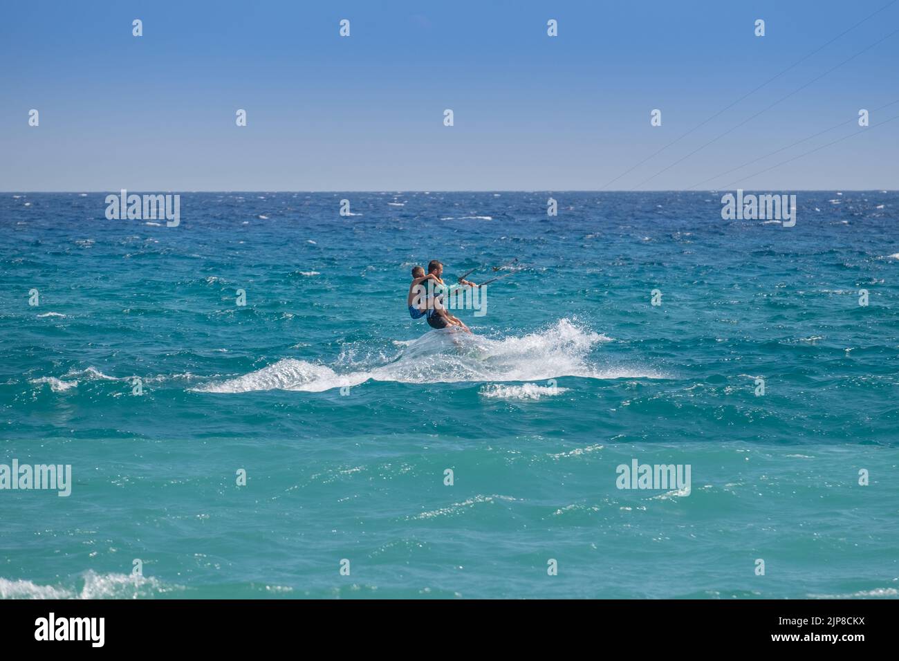 Man kitesurfing with a kid in his back in the sea of Agiokampos beach , Greece Stock Photo