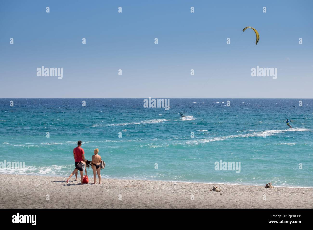 A family staring the kitesurfers surfing in the beach of Agiokampos , Greece Stock Photo